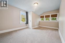 Additional living space featuring a textured ceiling, lofted ceiling, and light carpet - 