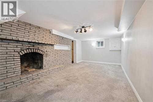Unfurnished living room featuring light carpet, a brick fireplace, and track lighting - 41 Rose Street, Kitchener, ON - Indoor With Fireplace