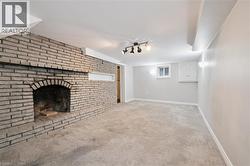 Unfurnished living room featuring light carpet, a brick fireplace, and track lighting - 