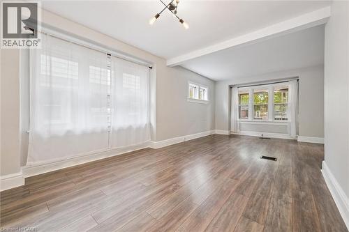 Empty room featuring wood finished floors, a chandelier, and beam ceiling - 41 Rose Street, Kitchener, ON - Indoor