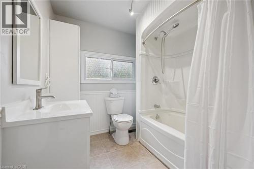 Full bathroom featuring shower / bath combo with shower curtain, vanity, wainscoting, and light tile patterned flooring - 41 Rose Street, Kitchener, ON - Indoor Photo Showing Bathroom