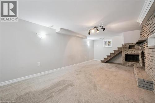 Finished basement featuring light carpet and a brick fireplace - 41 Rose Street, Kitchener, ON - Indoor Photo Showing Other Room With Fireplace