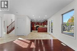Kitchen with reddish brown cabinets, recessed lighting, decorative backsplash, light countertops, and black appliances - 