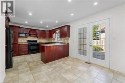 Kitchen featuring black appliances, a peninsula, recessed lighting, custom exhaust hood, and tasteful backsplash - 