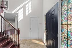 Entrance foyer with a towering ceiling, light tile patterned floors, and stairs - 