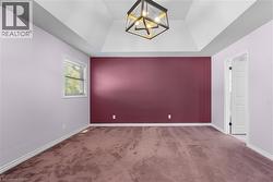 Spare room with a tray ceiling, carpet flooring, and a chandelier - 