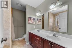 Bathroom featuring double vanity, a shower with shower curtain, and light tile patterned floors - 