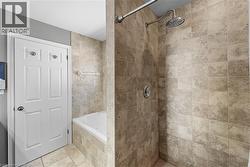 Bathroom with a tile shower, a relaxing tiled tub, and tile patterned floors - 