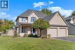 Traditional home with a shingled roof, asphalt driveway, brick siding, a porch, and an attached garage - 