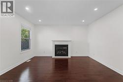 Unfurnished living room with recessed lighting, a glass covered fireplace, and dark wood-style floors - 