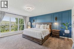 Primary retreat with a stylish feature wall, framed by breathtaking river views and a beautifully treed backdrop - 