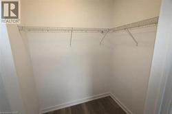 Spacious walk-in closet featuring dark wood-vinyl floors - 