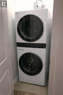 Laundry room featuring stacked washer and clothes dryer and light wood finished floors - 