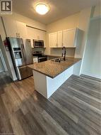 Kitchen featuring white cabinetry, refrigerator, a peninsula, range, and a textured ceiling - 