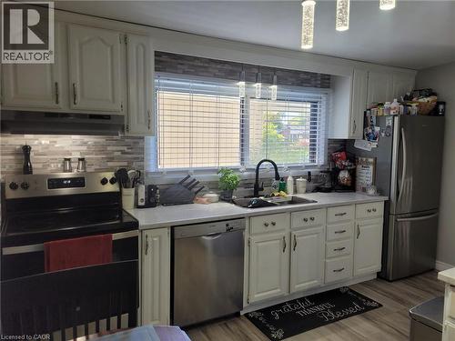 Kitchen with appliances with stainless steel finishes, tasteful backsplash, white cabinets, and under cabinet range hood - 89 Deschene Avenue, Hamilton, ON - Indoor Photo Showing Kitchen