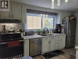 Kitchen with appliances with stainless steel finishes, tasteful backsplash, white cabinets, and under cabinet range hood - 