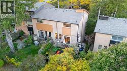 Rear view of house with a deck, brick siding, roof with shingles, and view of scattered trees - 