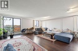 Living room featuring a textured ceiling, dark wood-type flooring, crown molding, and a baseboard radiator - 