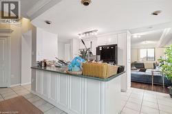 Kitchen with dark countertops, crown molding, light tile patterned floors, freestanding refrigerator, and white cabinetry - 