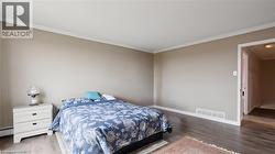 Bedroom with crown molding, wood finished floors, and a baseboard heating unit - 