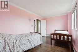 Bedroom with ornamental molding, dark wood-type flooring, a baseboard radiator, and a textured ceiling - 