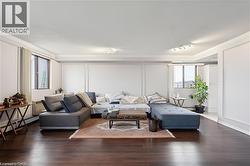 Living area with crown molding, a baseboard heating unit, wood finished floors, and a decorative wall - 