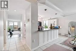 Kitchen with white cabinetry, dark countertops, light tile patterned floors, baseboard heating, and recessed lighting - 