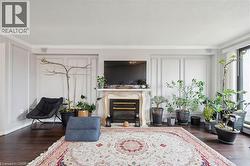 Living room with crown molding, dark wood-style floors, a glass covered fireplace, a decorative wall, and a textured ceiling - 