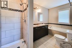 Bathroom with double vanity, light tile patterned flooring, plenty of natural light, and tiled shower / bath combo - 