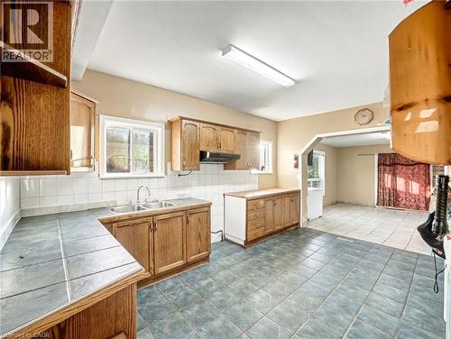 Kitchen with tasteful backsplash, brown cabinetry, and healthy amount of natural light - 23 Oak Avenue, Hamilton, ON - Indoor Photo Showing Kitchen With Double Sink