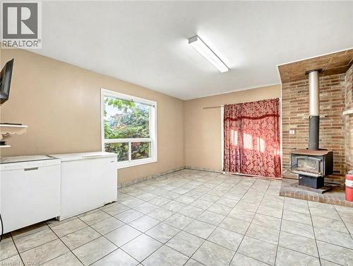 Unfurnished living room with a wood stove and light tile patterned floors - 23 Oak Avenue, Hamilton, ON - Indoor Photo Showing Other Room With Fireplace