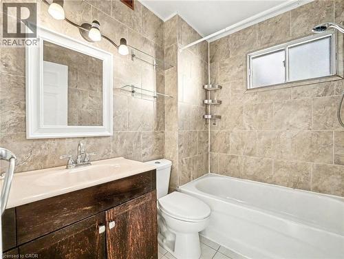 Bathroom with tile walls, shower / bathtub combination, vanity, and tile patterned flooring - 23 Oak Avenue, Hamilton, ON - Indoor Photo Showing Bathroom