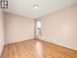 Unfurnished room featuring light wood-style flooring and a baseboard radiator - 