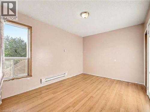 Spare room with light wood-style floors and a baseboard radiator - 23 Oak Avenue, Hamilton, ON - Indoor Photo Showing Other Room