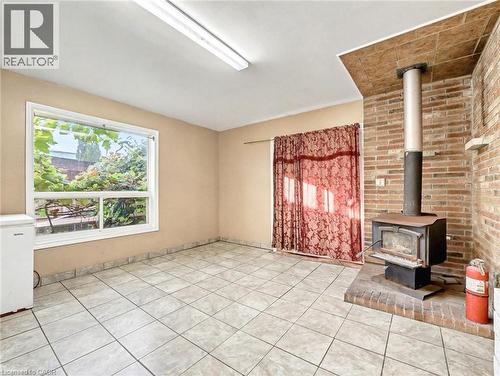 Unfurnished living room with a wood stove and light tile patterned floors - 23 Oak Avenue, Hamilton, ON - Indoor Photo Showing Other Room With Fireplace