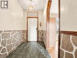 Entryway featuring dark tile patterned flooring, a chandelier, and a wainscoted wall - 