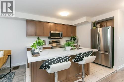 Kitchen featuring appliances with stainless steel finishes, a breakfast bar, a kitchen island, light wood finished floors, and brown cabinets - 386 Linden Drive, Cambridge, ON - Indoor Photo Showing Kitchen