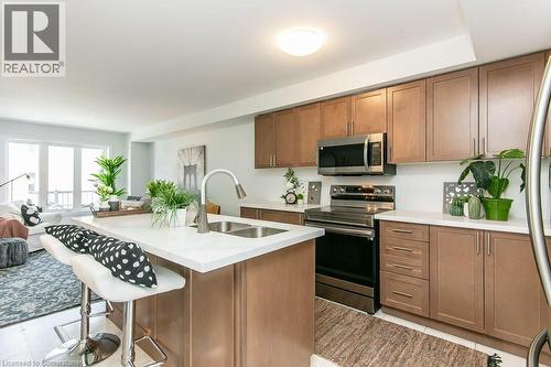 Kitchen with appliances with stainless steel finishes, a kitchen bar, brown cabinets, light countertops, and a kitchen island with sink - 386 Linden Drive, Cambridge, ON - Indoor Photo Showing Kitchen With Double Sink