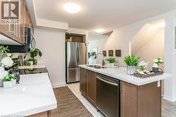 Kitchen featuring stainless steel appliances, light tile patterned flooring, and an island with sink - 