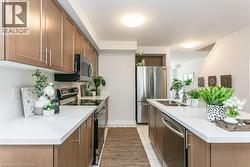 Kitchen with appliances with stainless steel finishes, light countertops, brown cabinetry, and light tile patterned flooring - 