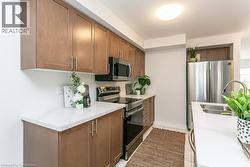 Kitchen featuring appliances with stainless steel finishes, light countertops, brown cabinets, and light tile patterned flooring - 