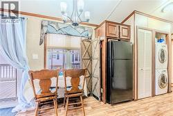 Dining area featuring light wood-type flooring, crown molding, estacked washer and dryer, and a chandelier - 