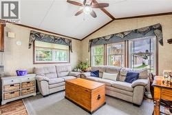 Living room featuring wood finished floors, lofted ceiling, ceiling fan, and ornamental molding - 