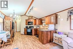 Kitchen featuring lofted ceiling, black appliances, light countertops, light wood-type flooring, and brown cabinets - 