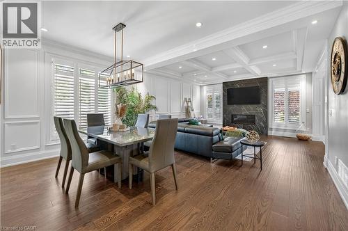 Dining room with healthy amount of natural light, dark wood-style floors, a high end fireplace, beamed ceiling, and recessed lighting - 18 David Avenue, Hamilton, ON - Indoor Photo Showing Dining Room With Fireplace