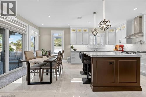 Kitchen featuring white cabinetry, glass insert cabinets, dark brown cabinets, tasteful backsplash, and wall chimney exhaust hood - 18 David Avenue, Hamilton, ON - Indoor Photo Showing Other Room