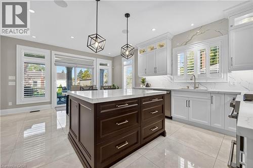 Kitchen with white cabinets, dark brown cabinetry, pendant lighting, light stone counters, and plenty of natural light - 18 David Avenue, Hamilton, ON - Indoor Photo Showing Kitchen With Upgraded Kitchen