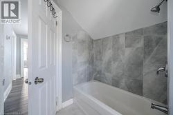 Bathroom with lofted ceiling and tiled shower / bath combo - 