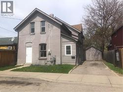 View of front of house with fence, a storage unit, brick siding, a garage, and driveway - 