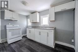 Kitchen with dark hardwood / wood-style flooring, sink, white electric range oven, and white cabinets - 